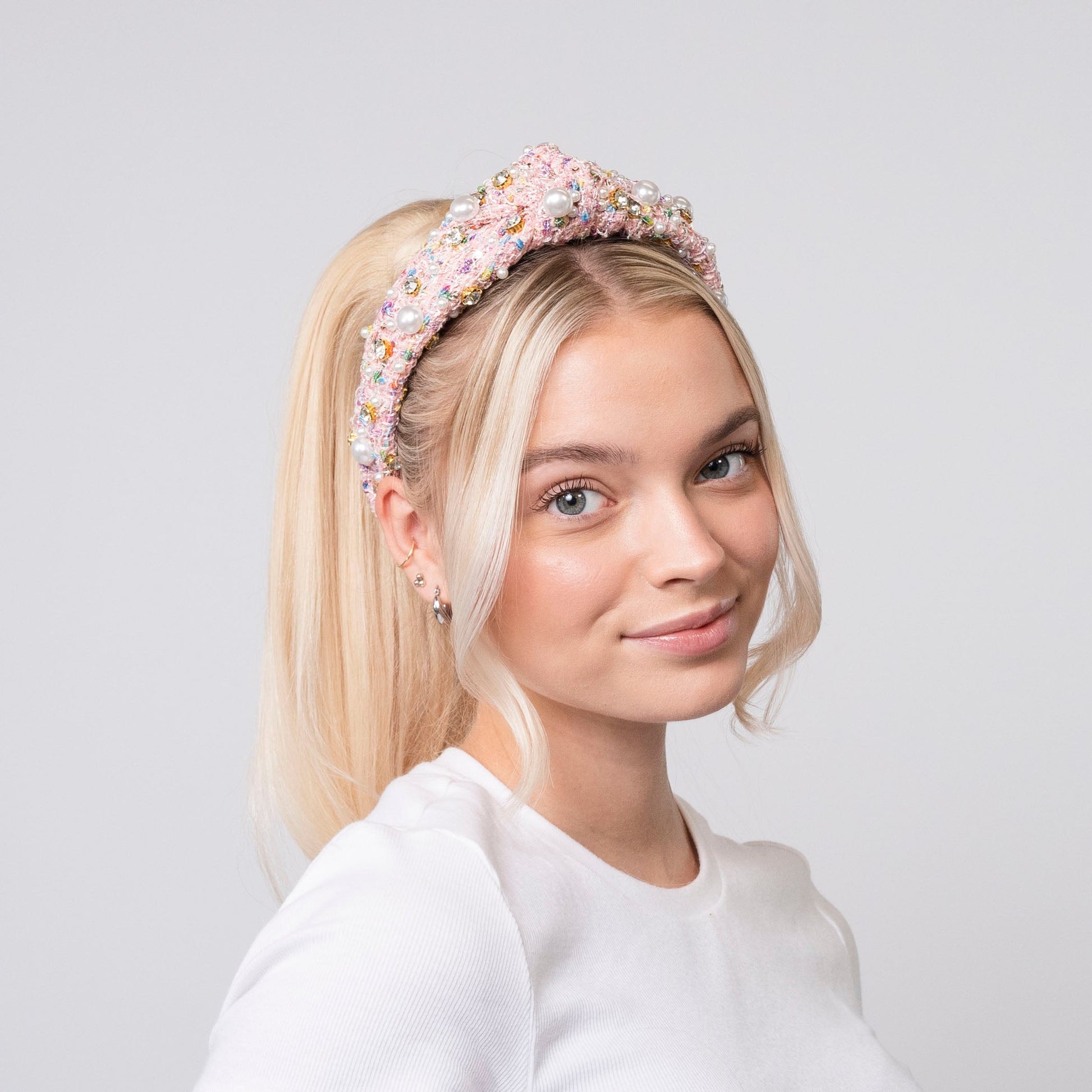 Woman wearing a textured pink headband against a plain background